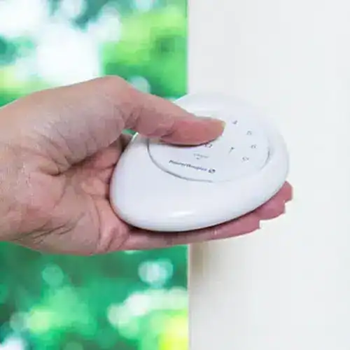 Close-up of hand pressing a wireless remote control for automatic door operation.