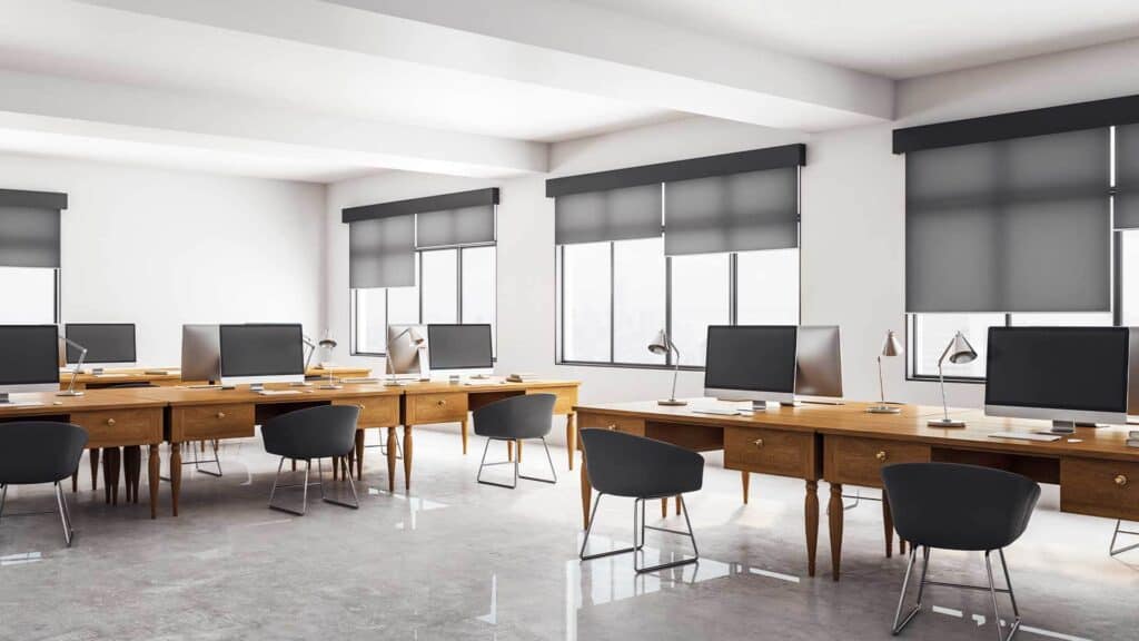 Bright office with large windows fitted with sleek, black commercial blinds providing privacy and light control in a professional workspace.