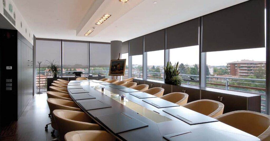 Commercial blinds installed in a corporate conference room with large windows and city view.